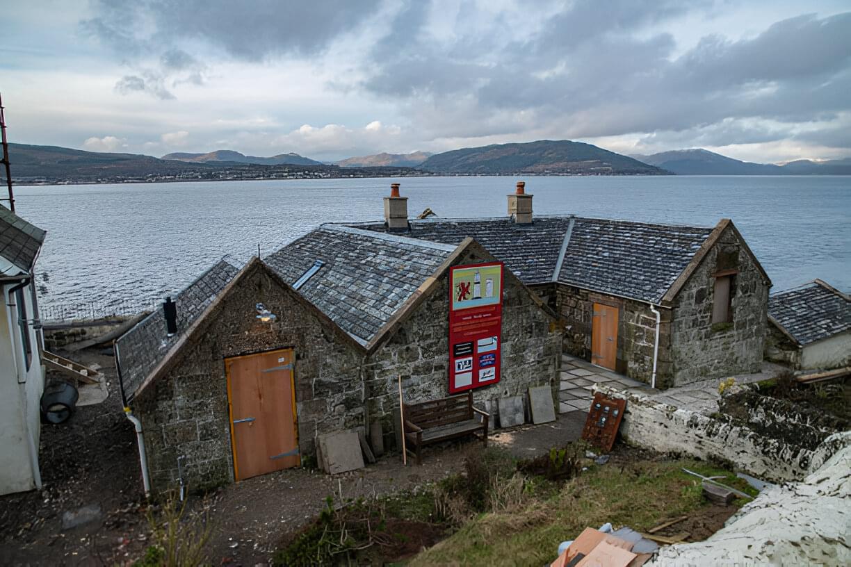 View of two old stone cottages with slate roofs, located by the sea in Scotland